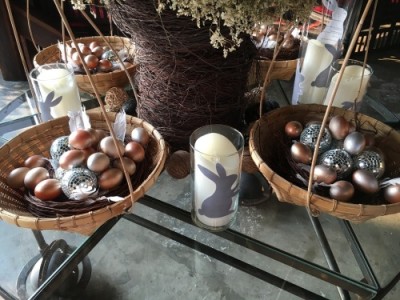 A velmi avantgardní je stolní výzdoba s proutěnými ošatkami s vejci, proutěnými a metalickými míčky, doplněná proutěnou vázou a sklenicemi s emblémem zajíčků.